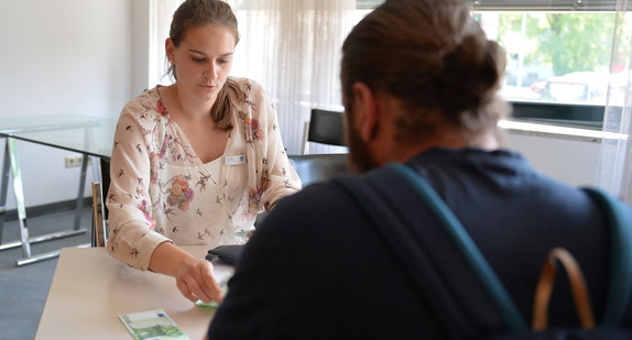 Eine Mitarbeiterin des Landratsamts Ostalbkreis zahlt einem Unwetteropfer Geld aus (Bild: © dpa).