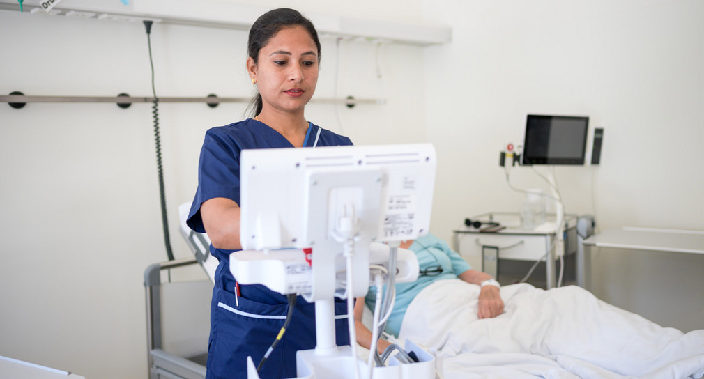 Eine indische Pflegekraft misst die Vitalwerte einer Patientin.