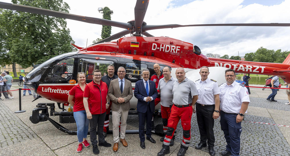 Innenminister Thomas Strobl und Stuttgarter Oberbürgermeister Dr. Frank Nopper umgeben von Personen vor einem Hubschrauber der Luftrettung. 
