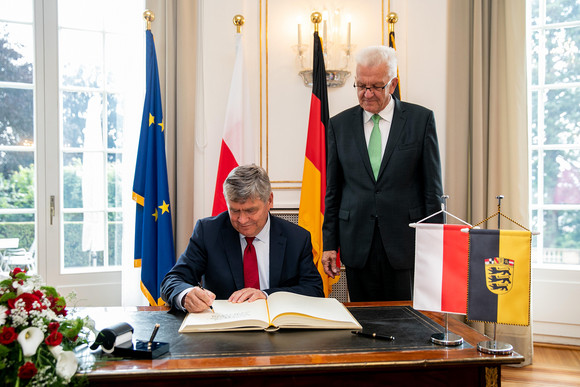 Woiwodschaftsmarschall Witold Stępień (l.) beim Eintrag in das Gästebuch der Landesregierung, daneben steht Ministerpräsident Winfried Kretschmann (r.)