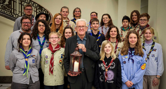 Gruppenbild mit Ministerpräsident Winfried Kretschmann (vorne in der Mitte) mit dem Friedenslicht in den Händen und jugendlichen Pfadfinderinnen und Pfadfindern