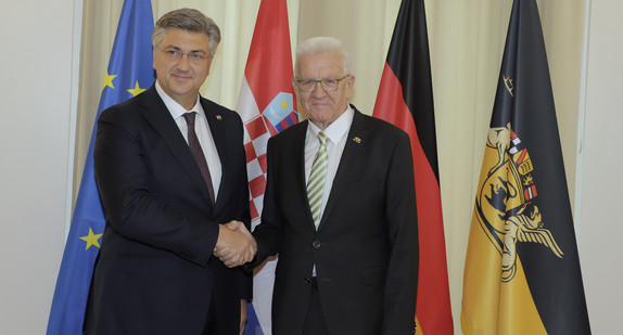 Ministerpräsident Winfried Kretschmann (rechts) und der kroatische Premierminister Andrej Plenković (links) stehen vor Fahnen und geben sich dabei die Hand.