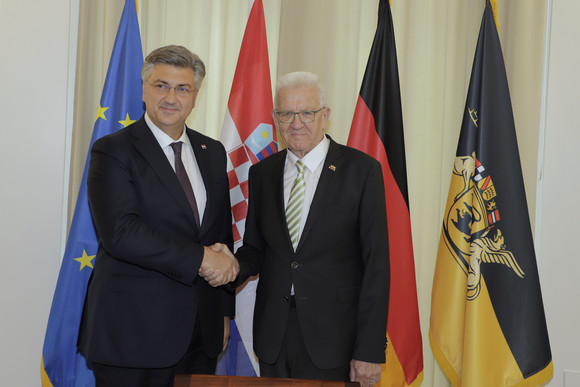 Ministerpräsident Winfried Kretschmann (rechts) und der kroatische Premierminister Andrej Plenković (links) stehen vor Fahnen und geben sich dabei die Hand.