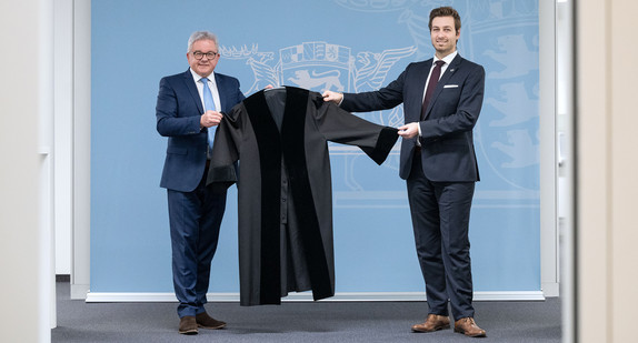 Justizminister Guido Wolf (l.) übergibt eine Robe an den Vorsitzenden des baden-württembergischen Landesverbands des Bundes Deutscher Rechtspfleger, Timo Haußern (r.)