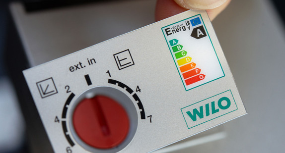 Eine Mitarbeiterin befestigt ein Energielabel an einer Pumpe. (Foto: Bernd Thissen dpa/lnw)