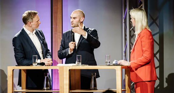 Finanzminister Dr. Danyal Bayaz, Bundesfinanzminister Christian Lindner und Moderatorin Sonja Álvarez Sobreviela stehen gemeinsam auf der Bühne und sind im Gespräch