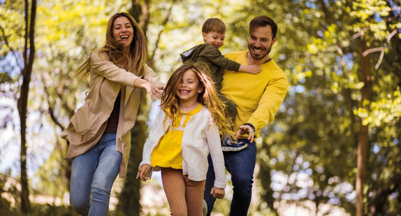 2 Kinder und 2 Erwachsene fröhlich im Wald