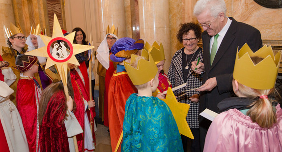 Ministerpräsident Winfried Kretschmann (r.) unterschreibt neben seiner Frau Gerlinde im neuen Schloss in Stuttgart Autogrammkarten für zahlreiche Sternsinger (Quelle: dpa).