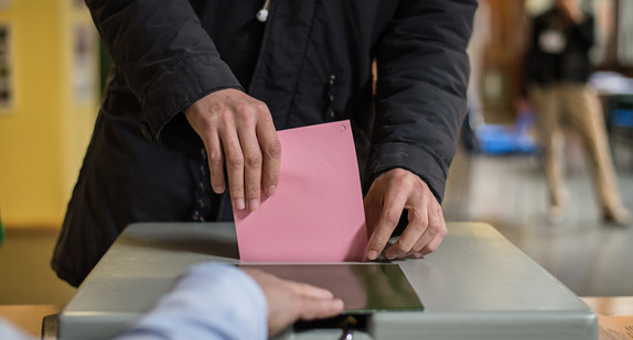 Ein Mann wirft seinen Stimmzettel in die Wahlurne.