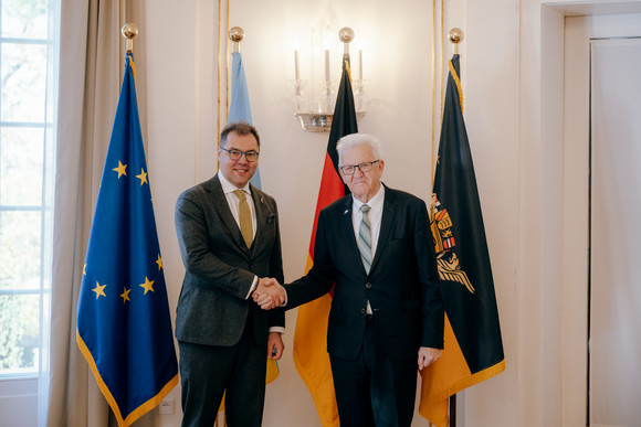 Ministerpräsident Winfried Kretschmann (rechts) und der ukrainische Botschafter Oleksij Makeiev (links) stehen vor Fahnen und geben sich die Hand.