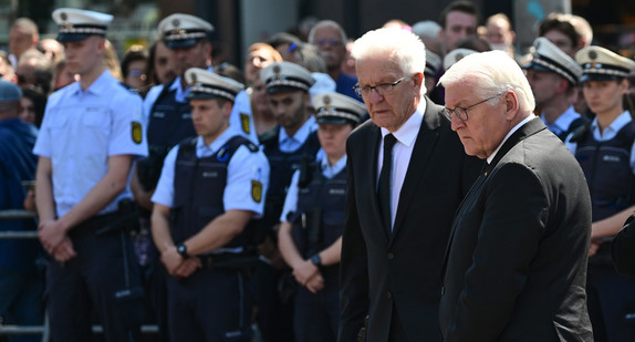Ministerpräsident Winfried Kretschmann (links) und Bundespräsident Frank-Walter Steinmeier (rechts) stehen bei einer Gedenkminute für den getöteten Polizisten auf dem Mannheimer Marktplatz.