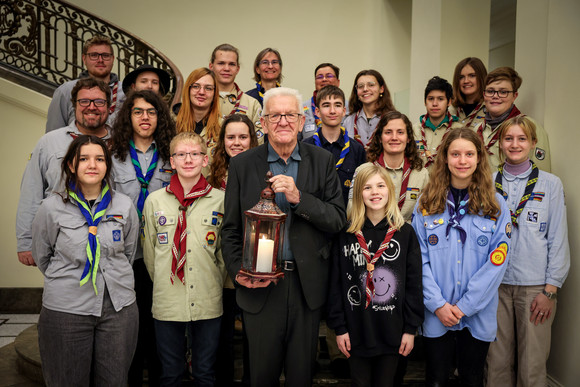 Gruppenbild mit Ministerpräsident Winfried Kretschmann (vorne in der Mitte) mit dem Friedenslicht in den Händen und jugendlichen Pfadfinderinnen und Pfadfindern