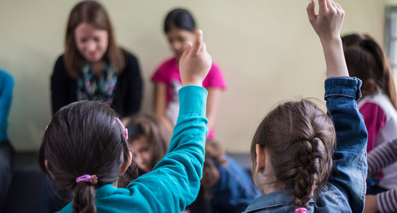 Schülerinnen und Schüler melden sich in einer Klasse.