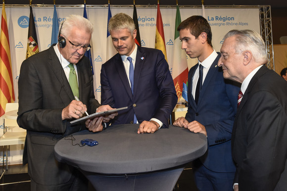 v.l.n.r.: Ministerpräsident Winfried Kretschmann, Laurent Wauquiez, Präsident der Region Auvergne-Rhône-Alpes, Giusseppe Cangialosi, Lombardei, und Marti Anglada, Katalonien, unterzeichnen auf einem Tablet eine gemeinsame Position der Vier Motoren für Europa zum künftigen Forschungsrahmenprogramm der EU (Foto: © Auvergne-Rhône-Alpes, Michel Pérès)