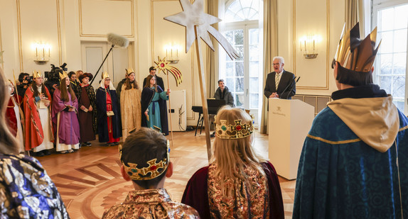 Ministerpräsident Winfried Kretschmann (hinten rechts) spricht zu den Sternsingerinnen und Sternsingern.