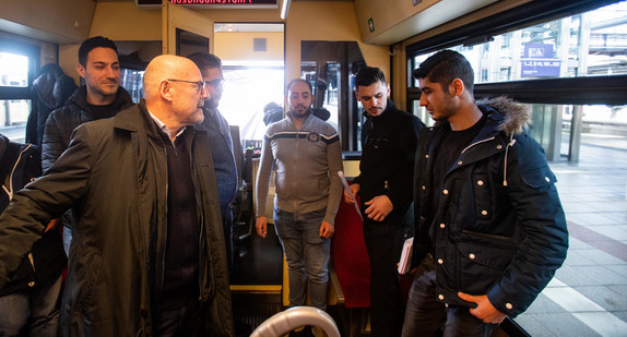 Verkehrsminister Winfried Hermann (2.v.l.) spricht in einem Triebwagen der AVG mit Flüchtlingen und ihrem Ausbilder. (Bild: © picture alliance/Philipp von Ditfurth/dpa)