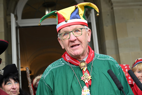 Ministerpräsident Winfried Kretschmann mit Narrenhemd und Narrenmütze vor dem Neuen Schloss in Stuttgart.