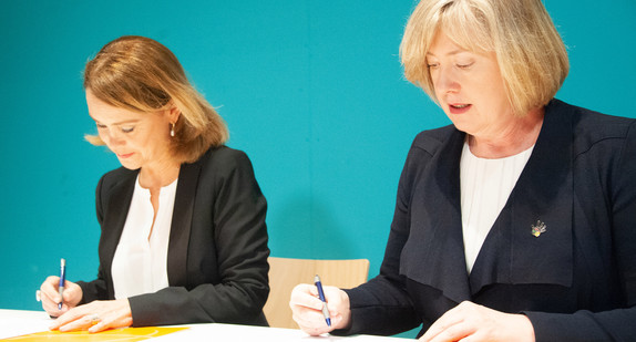 Kulturstaatssekretärin Petra Olschowski (l.), und die australische Botschafterin Lynette Wood (r.) unterschreiben ein Übergabeprotokoll (Bild: © picture alliance/Simon Sachseder/dpa)