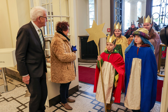 Ministerpräsident Winfried Kretschmann (links) und seine Ehefrau Gerlinde (zweite von links) begrüßen Sternsingerinnen und Sternsingern am Eingang der Villa Reitzenstein.