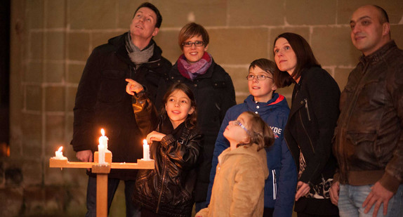 Eine Familie auf eine Führung bei Kerzenschein durch das Kloster Alpirsbach (Bild: © Staatliche Schlösser und Gärten Baden-Württemberg).