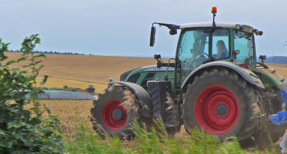 Eine Bäuerin fährt mit einem Traktor über ein Feld.