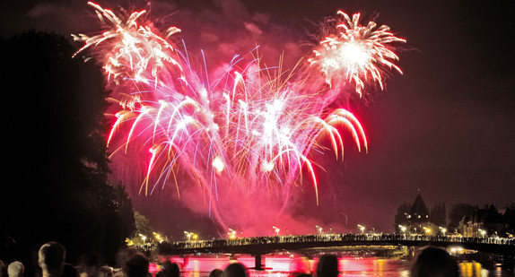 Menschen beobachten ein Feuerwerk in Konstanz am Bodensee (Bild: © dpa)