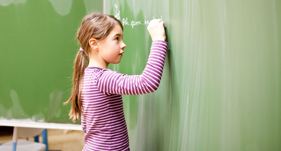 Grundschule Schülerin schreibt Satz an die Tafel