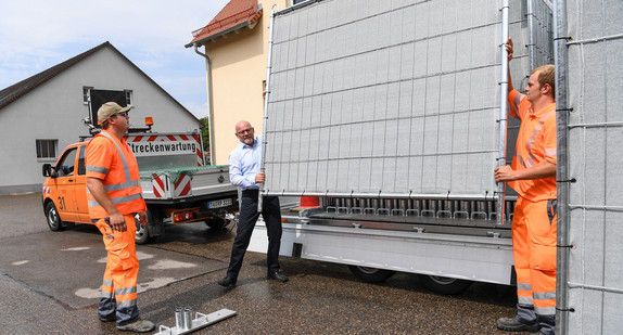 Verkehrsminister Winfried Hermann (M.) hilft in der Autobahnmeisterei, das neue Sichtschutzsystem gegen Neugierde aufzubauen. (Bild: © dpa)