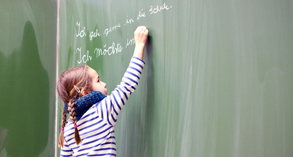 Grundschule Schülerin schreibt Satz an die Tafel