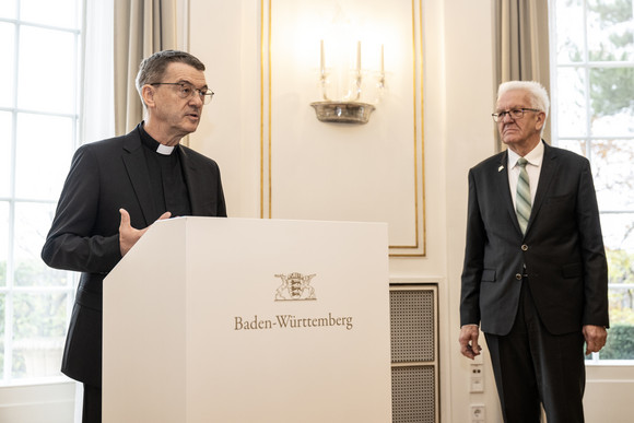 Der designierte Bischof von Rottenburg-Stuttgart, Prälat Dr. Klaus Krämer (links), bei seiner Ansprache, daneben steht Ministerpräsident Winfried Kretschmann (rechts).