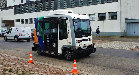 Kleiner autonomer Shuttle-Bus steht am Straßenrand.