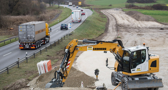 Fahrzeuge fahren an einem Bagger vorbei. (Foto: © dpa)