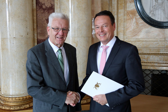 Ministerpräsident Winfried Kretschmann (l.) überreicht Klaus Tappeser (r.) die Ernennungsurkunde zum Regierungspräsidenten des Regierungsbezirks Tübingen.