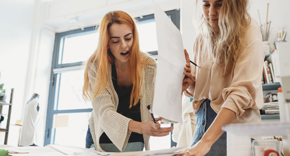 Zwei Künstlerinnen arbeiten an Entwürfen.