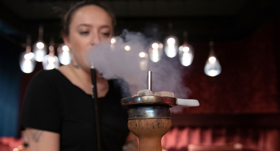 Eine Frau raucht eine Shisha in einer Shisha-Bar (Bild: © dpa).