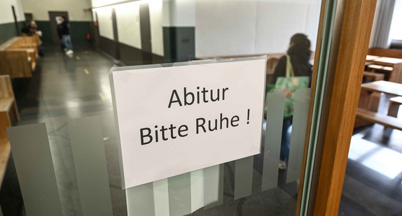 Eine Abiturienten des Spohn-Gymnasiums läuft an einem Schild mit der Aufschrift „Abitur - Bitte Ruhe!“ vorbei.