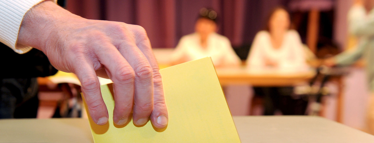 Ein Wahlzettel wird in eine Wahlurne geworfen. (Foto: © dpa)