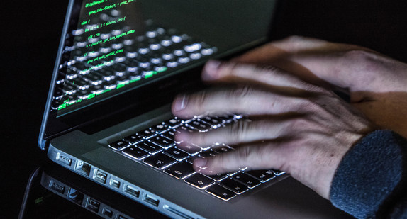 ILLUSTRATION - Ein Mann tippt auf einer beleuchteten Tastatur eines Laptops. (Bild: © dpa)