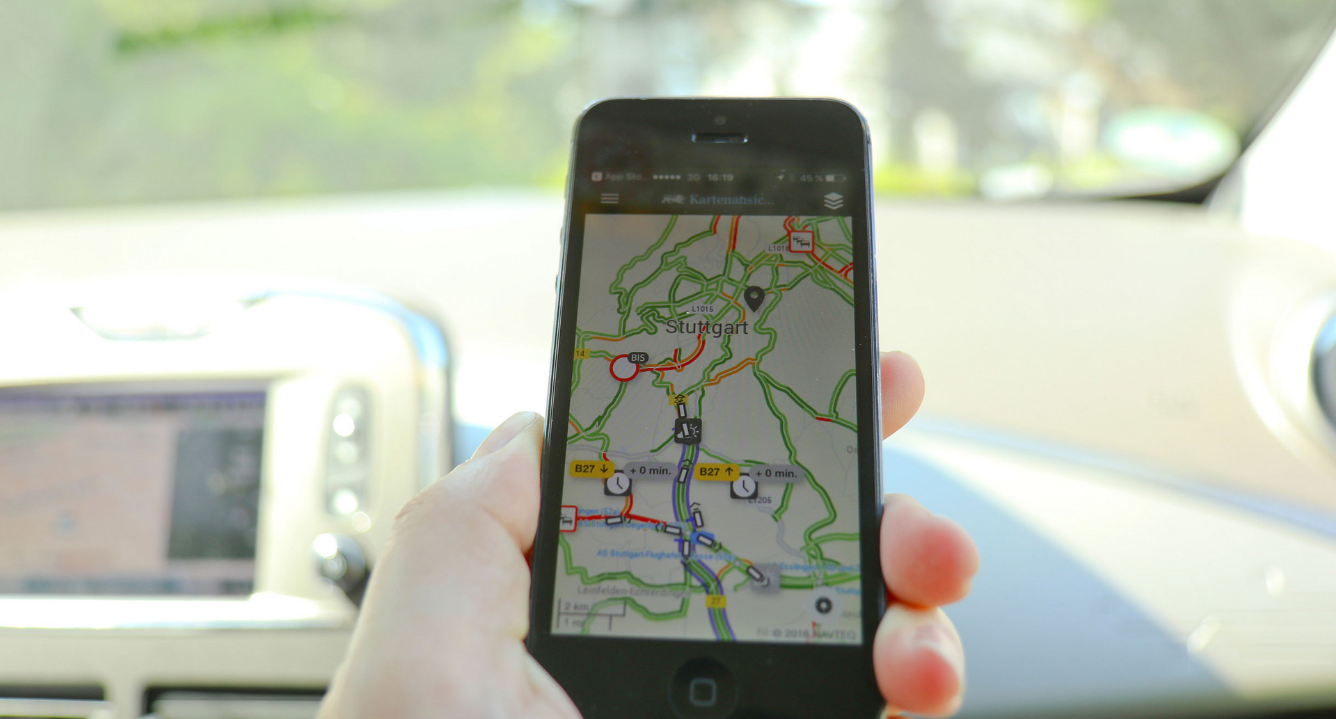 Jemand sitzt auf dem Beifahrersitz im Auto und hat auf dem Smartphone die App Verkehrsinfo BW laufen.