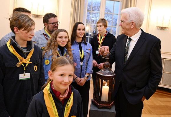 Jugendliche Pfadfinderinnen und Pfadfinder übergeben Ministerpräsident Winfried Kretschmann (rechts) das Friedenslicht aus Bethlehem.