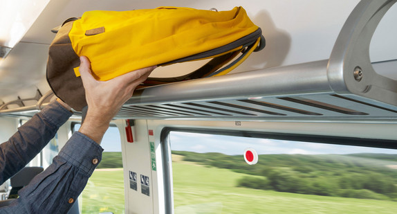 Rucksack wird auf die Gepäckablage über einen Sitz gelegt.