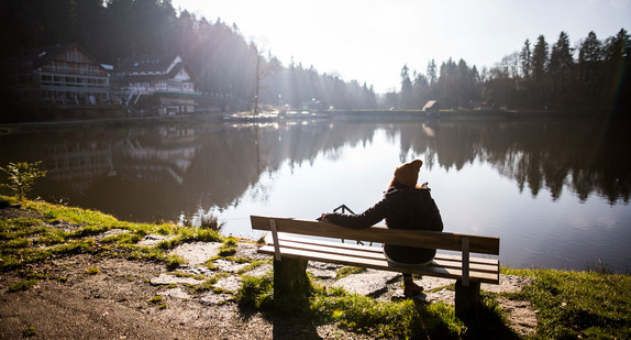 Eine junge Frau genießt die Sonnenstrahlen am Ebnisee bei Kaisersbach (Bild: © dpa).