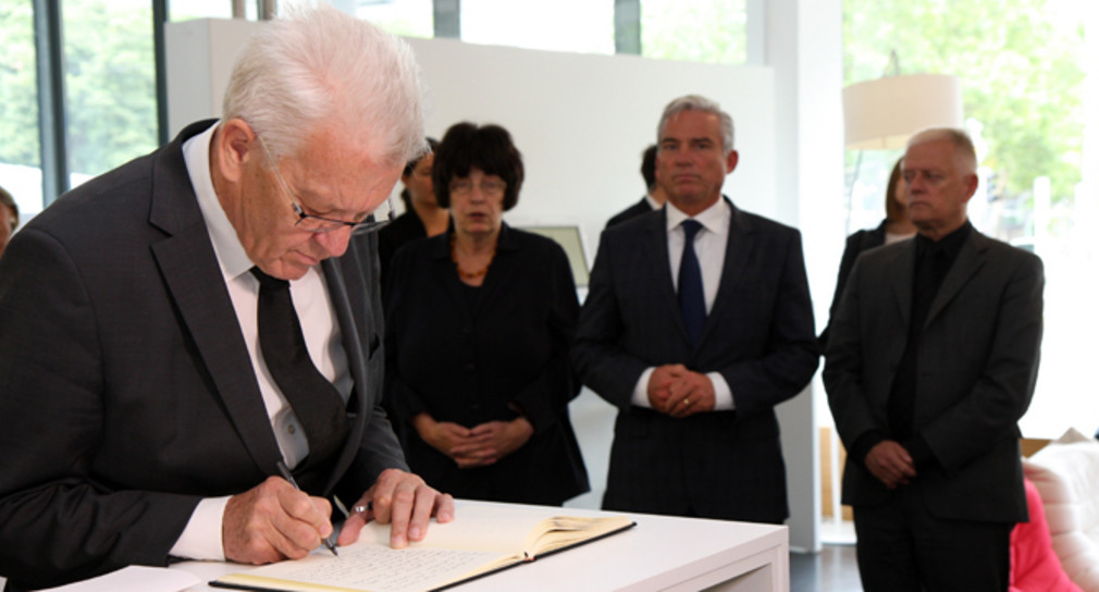 Ministerpräsident Winfried Kretschmann (l.) trägt sich in das Kondolenzbuch ein.