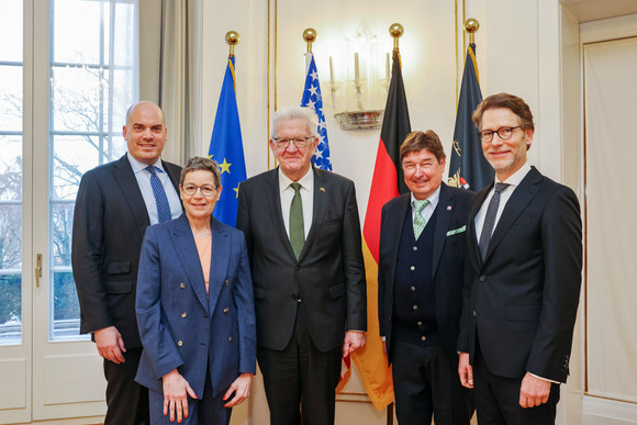 von links nach rechts: Daniel Andrich (AmCham Germany), Sabine Menne (Präsidentin AmCham Germany), Ministerpräsident Winfried Kretschmann, Prof. Dr. Gerhard Wegen (Chairman AmCham Baden-Württemberg), und Staatsminister Dr. Florian Stegmann stehen vor Fahnen.