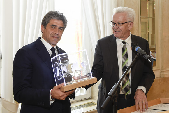 Ministerpräsident Winfried Kretschmann (r.) übergibt Staatssekretär Alan Christian Rizzi (l.), Lombardei, einen Kubus (Bild: Staatsministerium Baden-Württemberg)