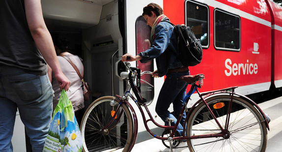 Eine Frau steigt mit ihrem Fahrrad in einen Zug.