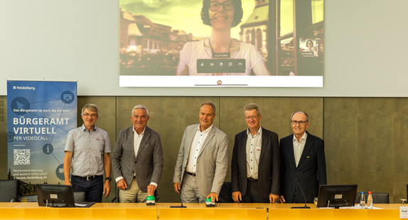 Startschuss für das „Bürgeramt Virtuell“ (von links): Manfred Leutz (Leiter Amt für Digitales, Stadt Heidelberg), Minister Thomas Strobl, Oberbürgermeister Prof. Dr. Eckart Würzner sowie Bernd Köster und Rudi Lerche (aktueller und ehemaliger Leiter des Bürgeramtes, Stadt Heidelberg). Auf dem Screen im Hintergrund und zugeschaltet ins „virtuelle Bürgeramt“: Ina Kindler (Bürger- und Ordnungsamt).