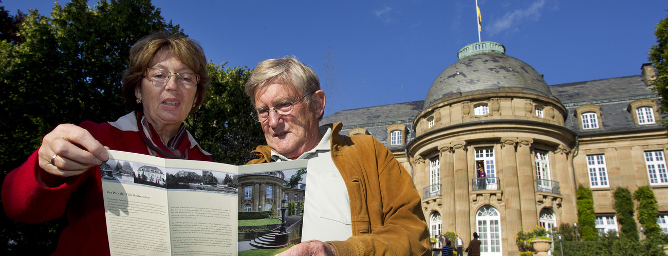 Deux personnes consultent une brochure dans le parc de la Villa Reitzenstein, résidence officielle du ministre-président.