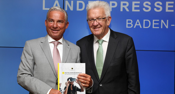 Ministerpräsident Winfried Kretschmann (r.) und Digitalisierungsminister Thomas Strobl (l.) mit einer gedruckten Version des ersten Digitalisierungsberichts der Landesregierung Baden-Württemberg