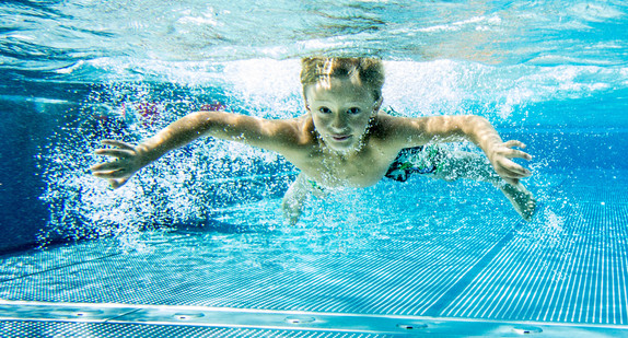 Ein Junge taucht im Freibad.